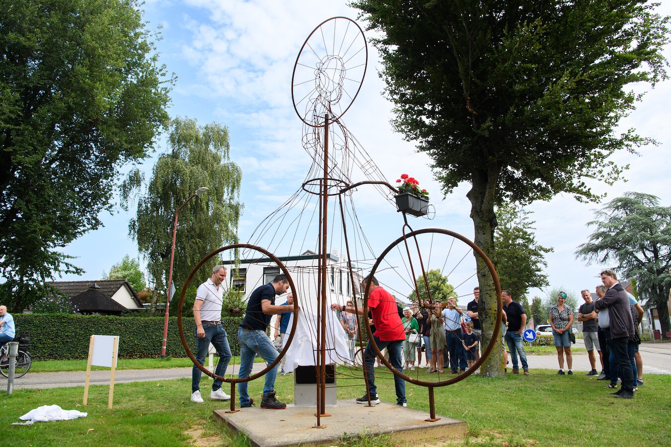 Onder toeziend oog van wethouder Bogers (links) onthullen bouwer Tom Akkermans en voorzitter van Corso Zundert Jos Jochems het bord bij het kunstwerk.