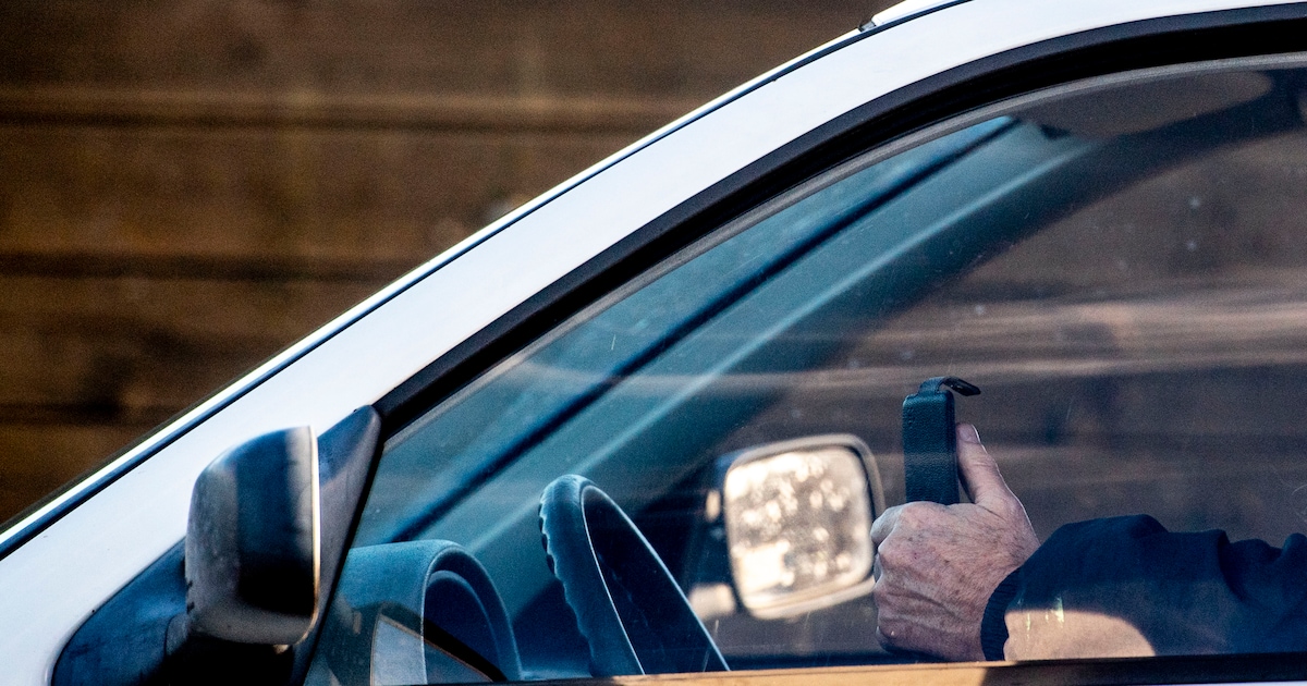 Bestuurder is bezig met telefoon en drukt bijna politieauto van de weg