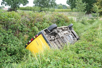 Pakketbus belandt op zijn kop in sloot in Dongen, bestuurder ongedeerd
