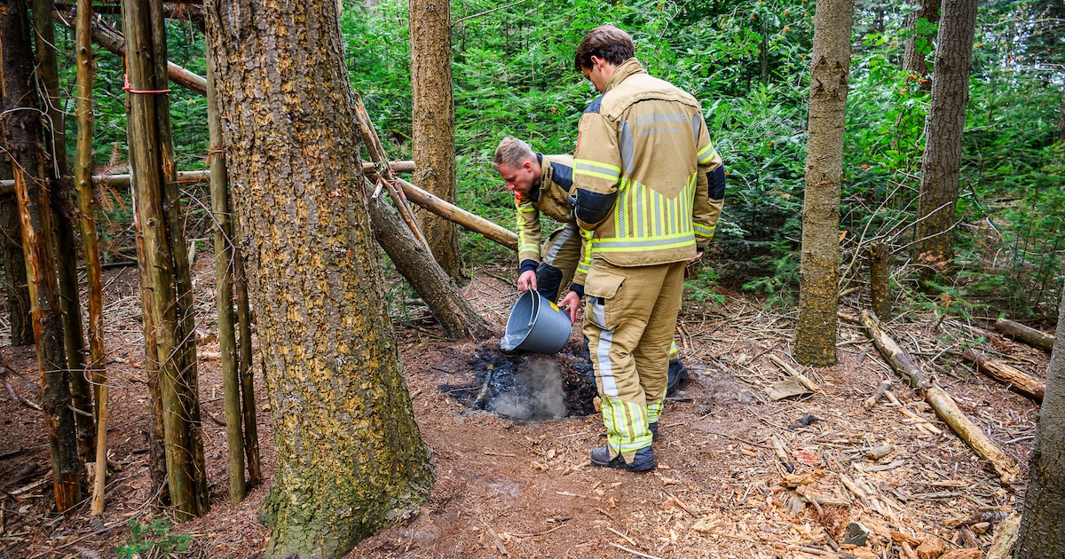 Brandweer blust smeulende resten van een kampvuur in bos bij Prinsenbeek