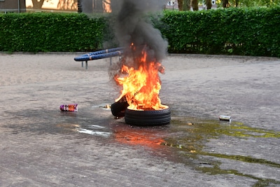 Autobanden in brand gestoken op speelplaats in Breda, buurtbewoners proberen te blussen met emmers w
